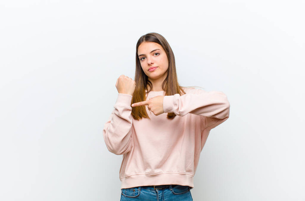 young pretty woman looking impatient and angry, pointing at watch, asking for punctuality, wants to be on time against white background - Photo, image