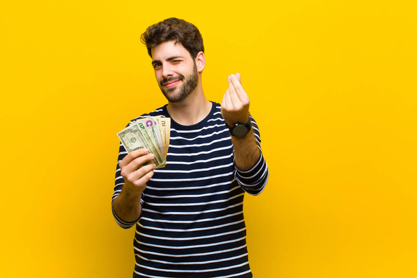 joven hombre guapo con billetes de dólar contra fondo naranja
 - Foto, Imagen