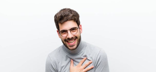 young manager man laughing out loud at some hilarious joke, feeling happy and cheerful, having fun against white wall - Photo, Image