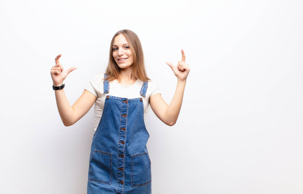 young pretty woman framing or outlining own smile with both hands, looking positive and happy, wellness concept against white wall - Фото, зображення