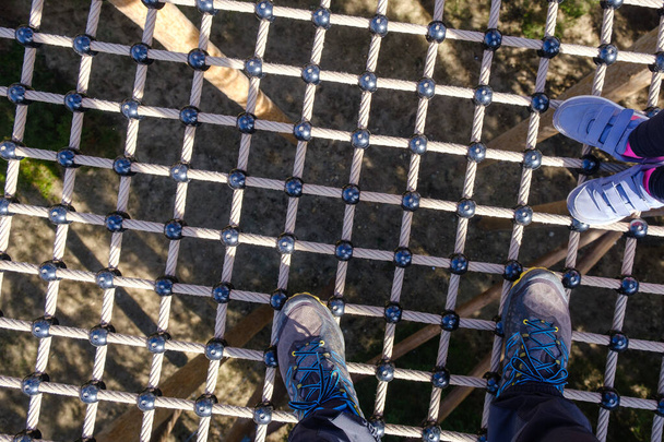 Feet of two people, urecognizable, standing on suspended walkway safety net - Photo, Image