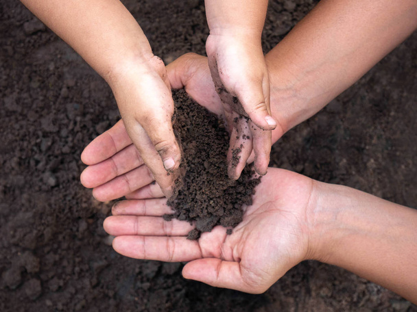 Close up of Woman and her child holding soil in hands. Environme - Photo, Image