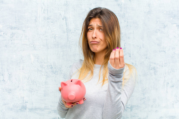 young pretty woman with a piggy bank against grunge wall - Fotoğraf, Görsel