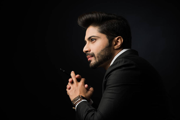 Indian bearded Male businessman showing side profile, standing over black background - Photo, Image