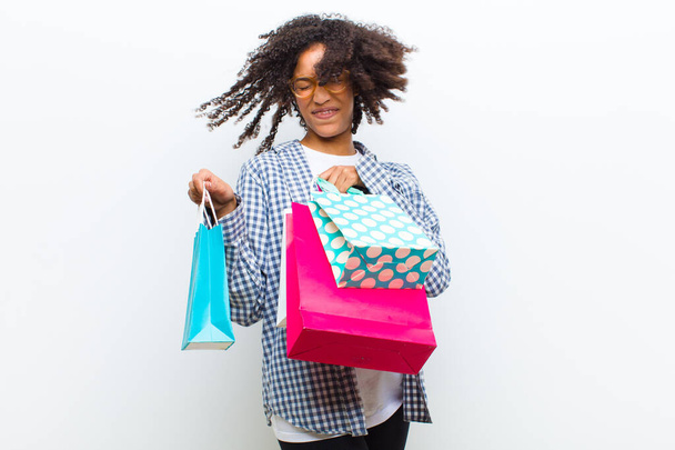 young pretty black woman with shopping bags against white wall - Foto, afbeelding