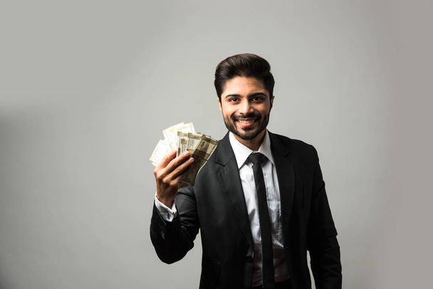 Щасливий індійський комерсант, який тримає в руках вентилятор, індійський долар Рупі 500 доларів, стоїть ізольований від білого фону. - Фото, зображення
