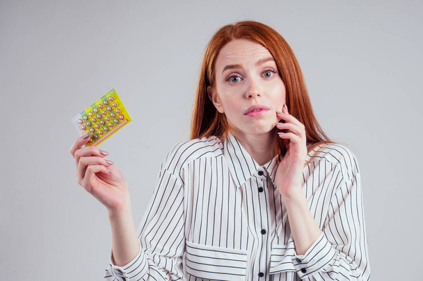 picture of young redhead businesswoman in striped shirt with one pack of pills white background studio - Photo, image
