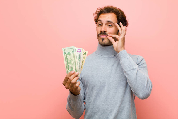 young handsome man with dollar banknotes against pink flat wall - Foto, Bild