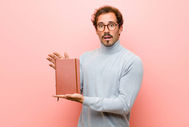 junger gutaussehender Mann mit Notizbuch gegen rosa Flachwand - Foto, Bild