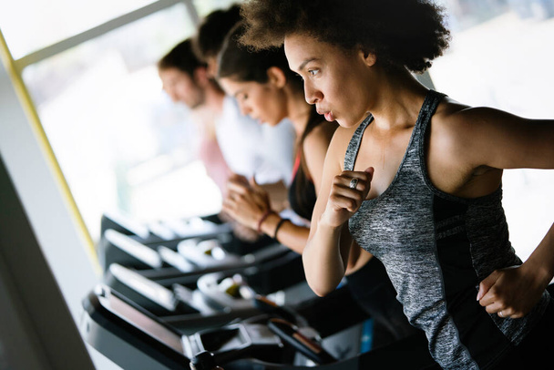 Happy fit people running on treadmill at modern fitness gym club - Фото, зображення