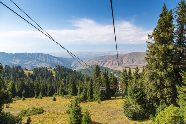 Літній гірський пейзаж високо в горах. Високі дерева ялинки, підйомник на гірськолижній базі
. - Фото, зображення
