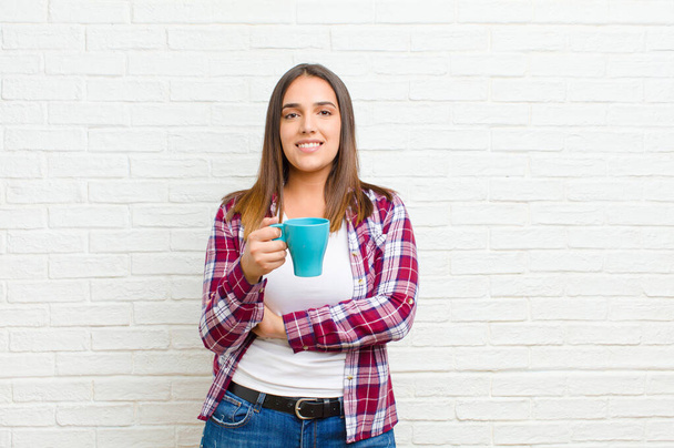 mujer bonita joven con un café contra la textura de la pared de ladrillo
 - Foto, imagen