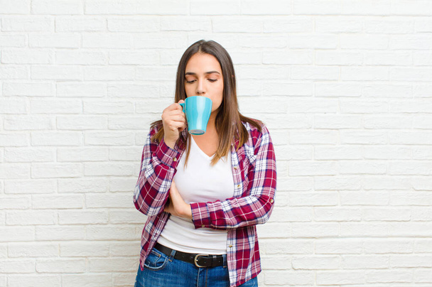 young pretty woman with a coffee against brick wall texture - Φωτογραφία, εικόνα
