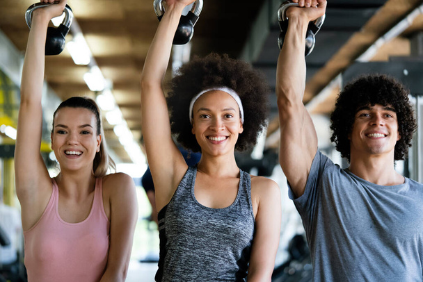 Group of happy fit friends exercising together in gym - Foto, afbeelding