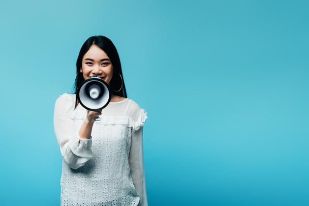 mosolygós barna ázsiai nő gazdaság hangszóró kék háttér - Fotó, kép
