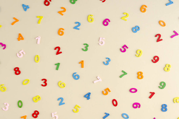 Colored wooden numbers composition on beige background. - Foto, afbeelding