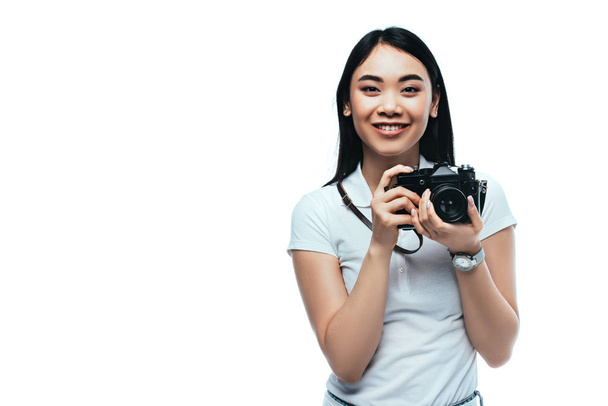 smiling brunette asian woman taking picture on digital camera isolated on white - Foto, Imagem