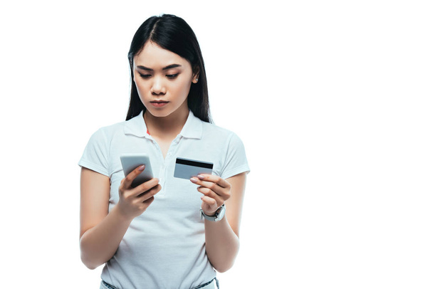 grave brunette asiatique fille tenant carte de crédit et smartphone isolé sur blanc
 - Photo, image