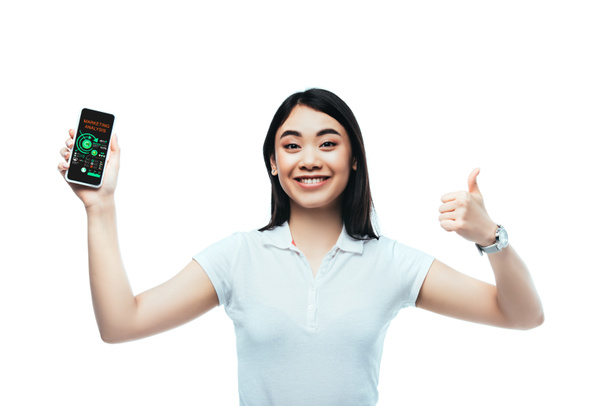 幸せなブルネットアジアの女性はマーケティング分析アプリでスマートフォンを保持し、白に隔離された親指アップサインを表示 - 写真・画像