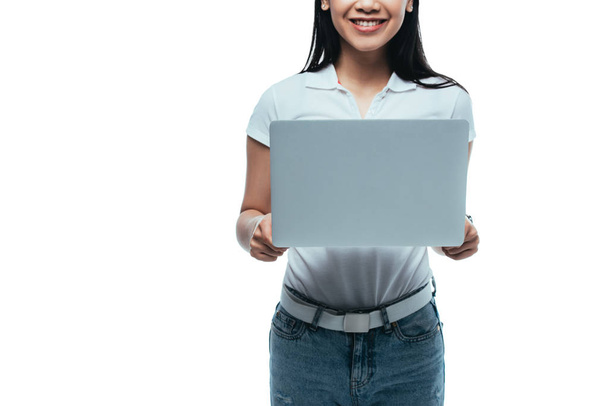 обрізаний вид усміхненої азіатської дівчини з ноутбуком ізольовано на білому
 - Фото, зображення