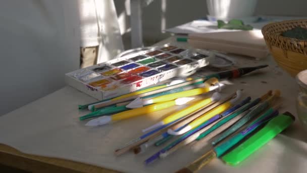 művész szakma, női festő kezét választani kefe közelében paletta festékek rajz a munkaterem közelkép - Felvétel, videó