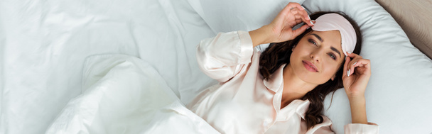 plano panorámico de mujer atractiva con máscara de dormir mirando a la cámara por la mañana
  - Foto, Imagen