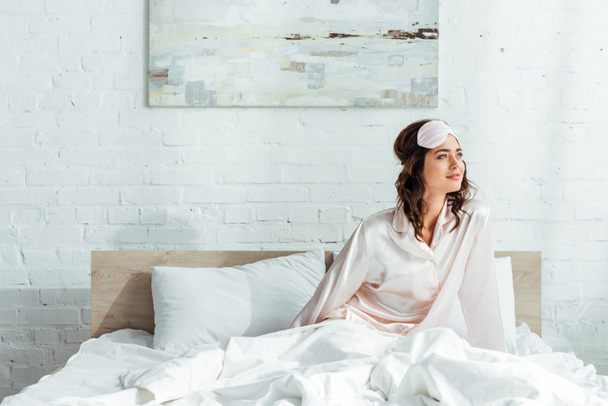 ελκυστική γυναίκα με μάσκα ύπνου κοιτάζοντας μακριά το πρωί  - Φωτογραφία, εικόνα
