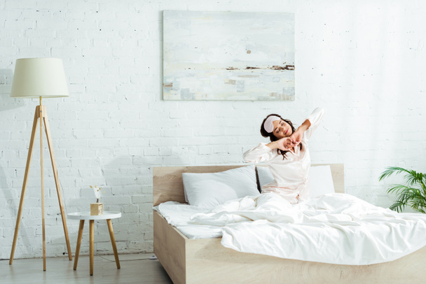 attractive woman in sleeping mask stretching herself at morning  - Photo, Image