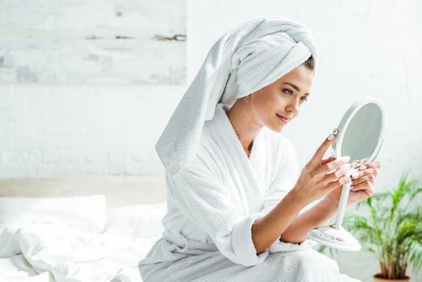 mujer atractiva en albornoz y toalla mirando el espejo por la mañana
  - Foto, Imagen