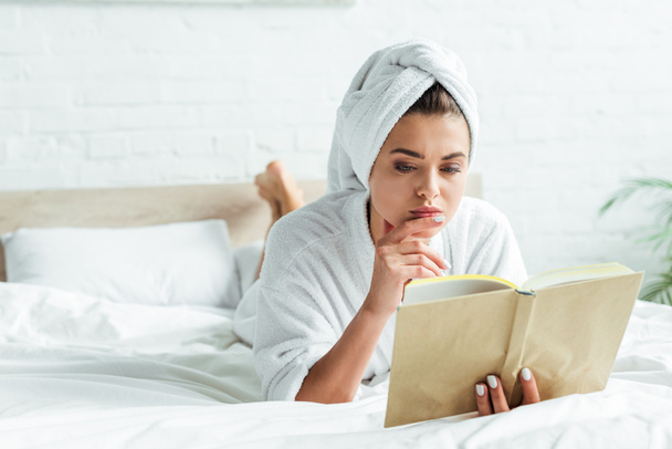 attractive woman in towel and bathrobe reading book at morning  - Fotó, kép