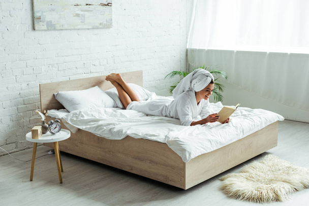 attractive woman in towel and bathrobe reading book at morning  - Фото, зображення