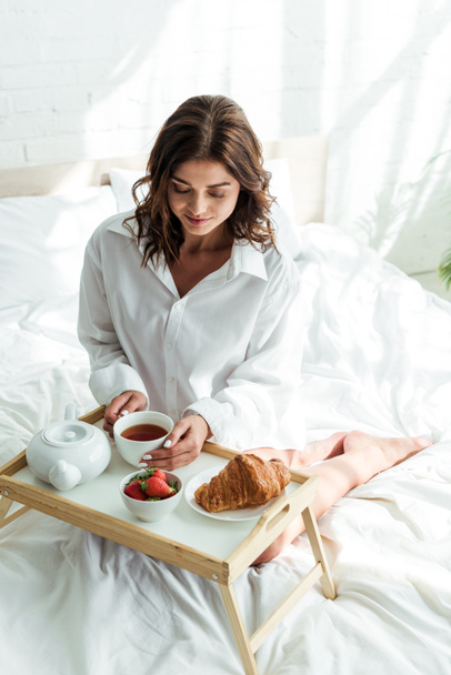 attractive woman in white shirt having breakfast in bed at morning  - Foto, immagini