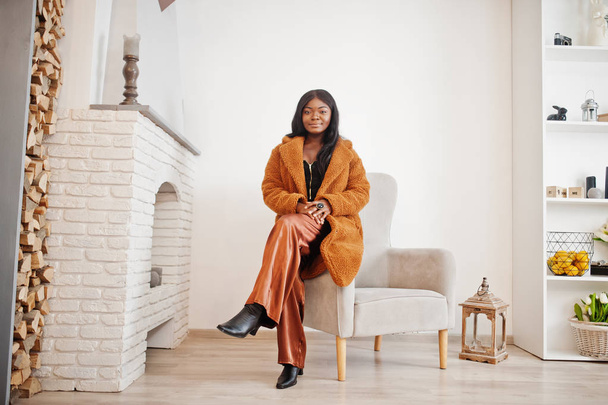 Stylish african american woman in orange coat posed at room agai - Photo, image