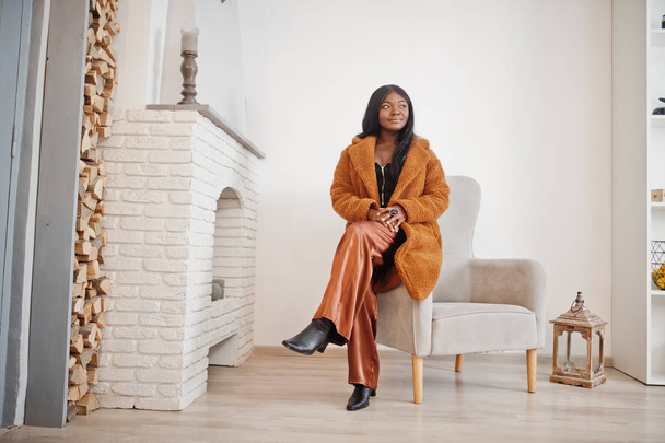 Stylish african american woman in orange coat posed at room agai - Photo, Image