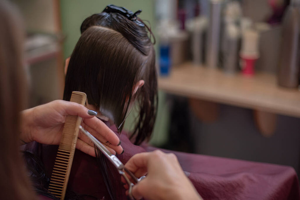 Peluquería estilista hace un peinado para una niña linda en un salón de belleza. - Foto, Imagen