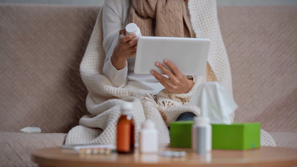 częściowy widok chorej kobiety stosującej tabletki w pobliżu tabeli z lekami - Materiał filmowy, wideo