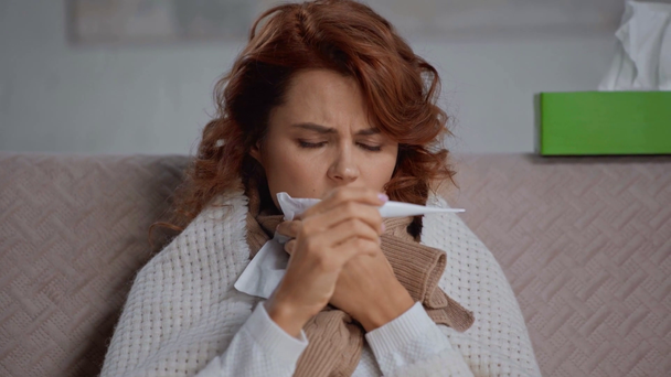 rack εστίαση της άρρωστης γυναίκας κοιτάζοντας θερμόμετρο και φτάρνισμα - Πλάνα, βίντεο