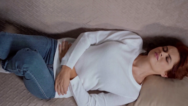 pohled shora na ženu ležící na pohovce a trpící bolestí břicha - Záběry, video