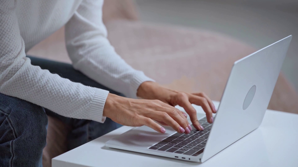 recortado de la mujer sentada en el sofá y escribiendo en el ordenador portátil
  - Metraje, vídeo