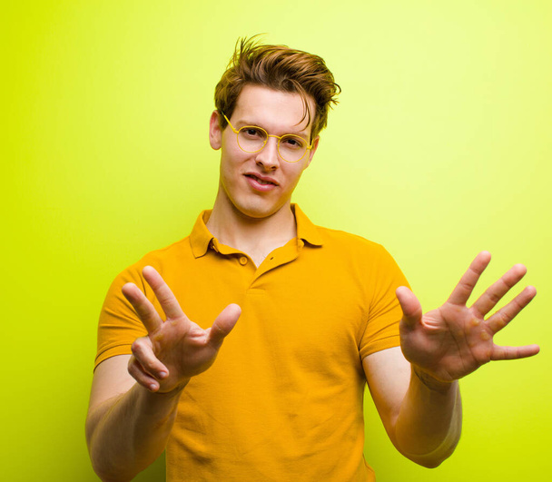 young red head man smiling and looking friendly, showing number eight or eighth with hand forward, counting down against chroma wall - Foto, immagini