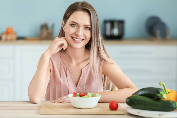 Young woman eating healthy vegetable salad in kitchen. Diet concept - Фото, зображення