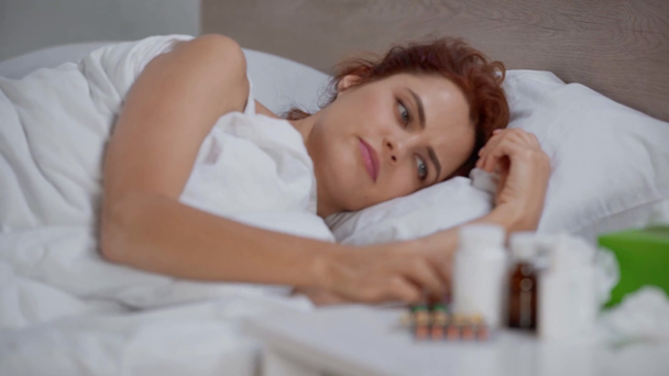 хвора, засмучена жінка вимірює температуру з термометром у ліжку
 - Кадри, відео