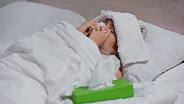 zieke vrouw hoesten terwijl liggend onder deken met handdoek op het hoofd  - Video