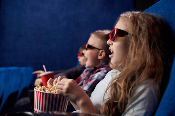 Geschokt meisje met vrienden kijken film in filmhuis - Foto, afbeelding