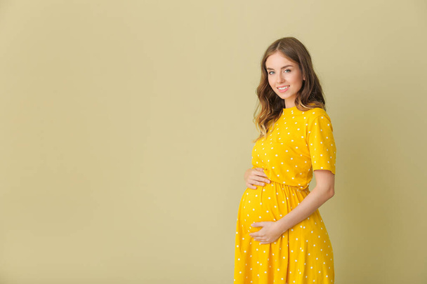 Mooie zwangere vrouw op kleur achtergrond - Foto, afbeelding