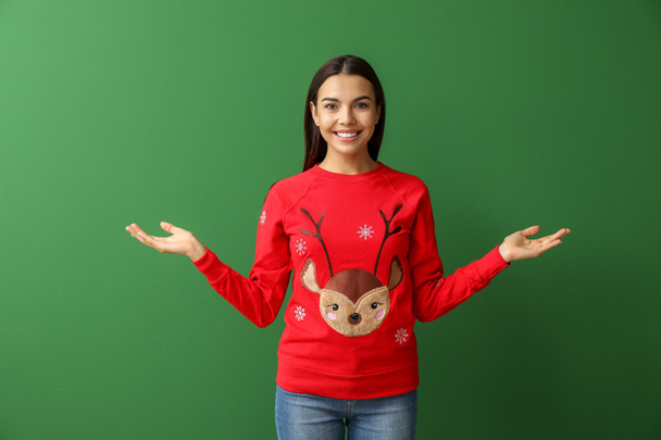 Mladá žena v vánoční svetr na barevném pozadí - Fotografie, Obrázek