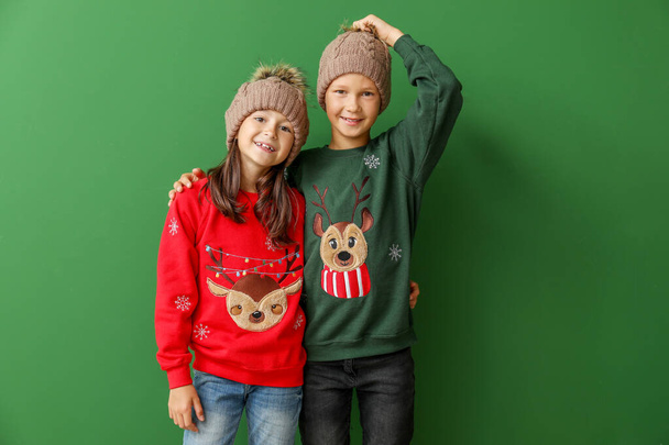 Kleine Kinder in Weihnachtspullis und Strickmützen auf farbigem Hintergrund - Foto, Bild
