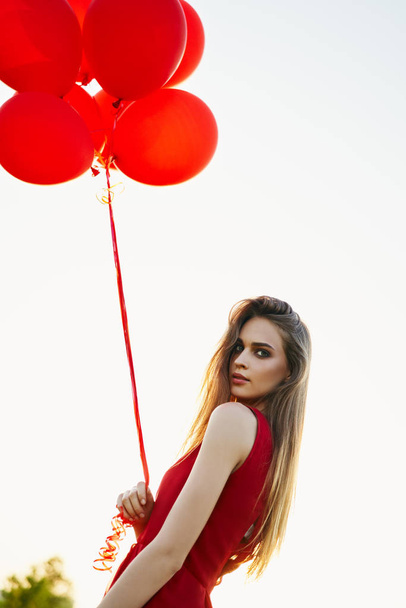 young woman with red balloons posing outdoors - Fotó, kép
