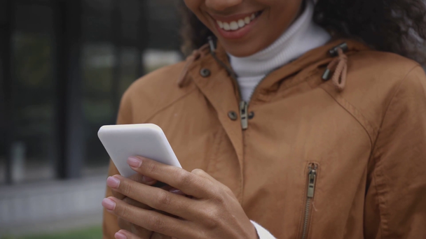 обрезанный вид улыбающейся африканской американки с помощью смартфона на улице
  - Кадры, видео