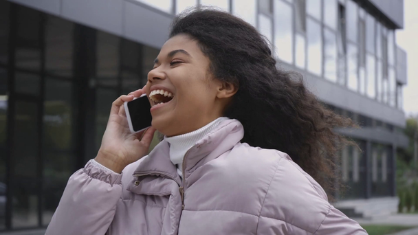 souriant afro-américaine parler sur smartphone tout en marchant dans la rue
 - Séquence, vidéo